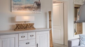 Una habitación con un armario blanco, una lámpara, un cuadro y una puerta con la leyenda 'BEACH'.