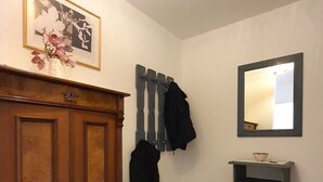 Una stanza con un armadio in legno, uno specchio e un pavimento piastrellato.