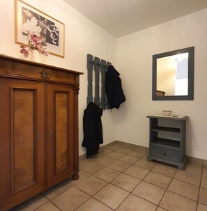 A room with a wooden cabinet, a mirror, and a tiled floor.