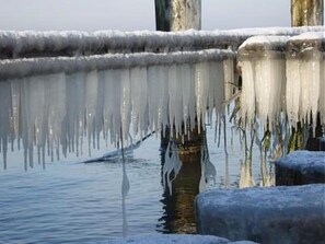 Des glaçons pendent d’une structure en bois au-dessus de l’eau.