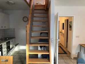 A staircase leading to a second floor with a kitchen area below.