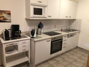 A compact kitchen with a microwave, toaster, coffee maker, and a dishwasher.
