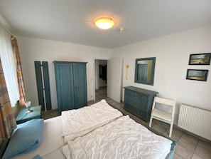 Quarto com cama, guarda-roupa, penteadeira e espelho.