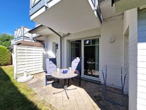 A patio with a table and chairs, a blue folding chair, and a blue laundry stand. - Darßer Weg 36 Whg. 9 - Holiday apartment near the beach (Zingst)
