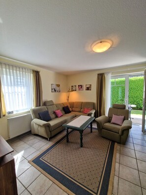 A living room with a sofa, armchairs, a coffee table, and a radiator.