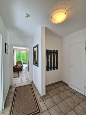 A hallway with a tiled floor, a doormat, a door, and a light fixture. - Darßer Weg 36 Whg. 9 - Holiday apartment near the beach (Zingst)