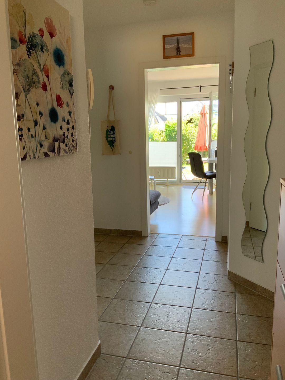 A hallway with a tiled floor leading to a dining area with a table and chairs.