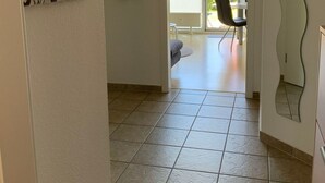 Ein Flur mit Fliesenboden, der zu einem Essbereich mit Tisch und Stühlen führt.
