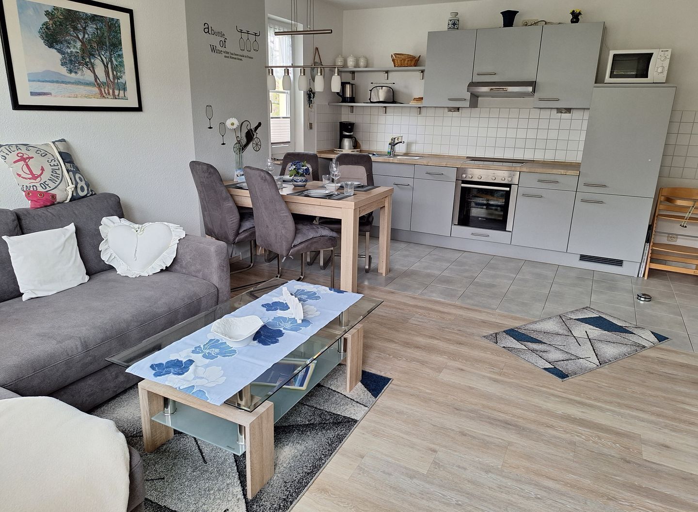 A compact living space with a dining area, kitchenette, and a sofa with decorative pillows. - Hafenstrasse 28 Whg. 3 - Lovingly furnished, sun-drenched 3-room apartment (Zingst)