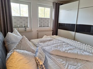 A bedroom with a bed, a window with blinds, a radiator, and a TV on a stand. - Hafenstrasse 28 Whg. 3 - Lovingly furnished, sun-drenched 3-room apartment (Zingst)