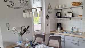 Uma cozinha moderna com armários brancos, uma mesa de jantar de madeira para quatro pessoas e uma ilha de cozinha.