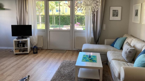 A living room with a sofa, a coffee table, a TV, and a large window with curtains. - Martha-Müller-Grählert-Weg 7/8 Whg.6 - Very nice, friendly and modern (Zingst)