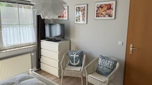 A bedroom with a bed, a TV on a dresser, two wicker chairs, and wall art. - Martha-Müller-Grählert-Weg 7/8 Whg.6 - Very nice, friendly and modern (Zingst)