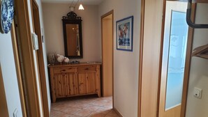 Ein Flur mit einem Holzkasten, einem Spiegel und einem gerahmten Bild an der Wand.