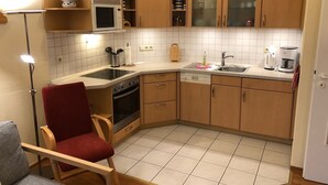 Une cuisine compacte avec des meubles en bois, un four à micro-ondes, un évier et un lave-vaisselle.
