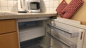 Une cuisine équipée d’une machine à café, d’un manique à carreaux et d’un réfrigérateur avec des étagères transparentes.