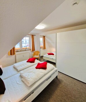 Une chambre avec deux lits, une armoire, un radiateur et une fenêtre avec des rideaux.