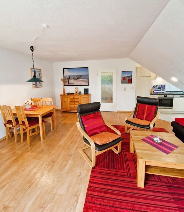 A spacious loft with a dining area, two lounge chairs, a kitchen, and a view of the beach.