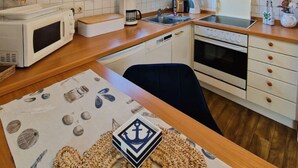 Ett modernt kök med vita skåp, en bänkskiva i trä, en mikrovågsugn, en spis och ett fönster med utsikt.