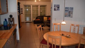 A compact kitchen with a dining area, featuring a round wooden table, chairs, and a coffee maker. - Birkenstrasse 21c Whg. 19 "Strandtraum" - Spacious, comfortable, freshly renovated (Zingst)