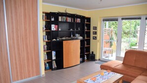 A living room with a sofa, a coffee table, and a bookshelf. - Birkenstrasse 21c Whg. 19 "Strandtraum" - Spacious, comfortable, freshly renovated (Zingst)