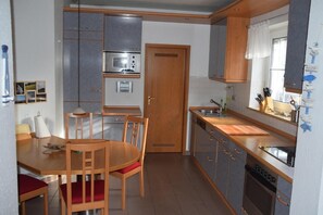 Eine kompakte Küche mit Holzausbau, einem Einbauofen, einer Spüle und einem Essbereich mit Tisch und Stühlen.