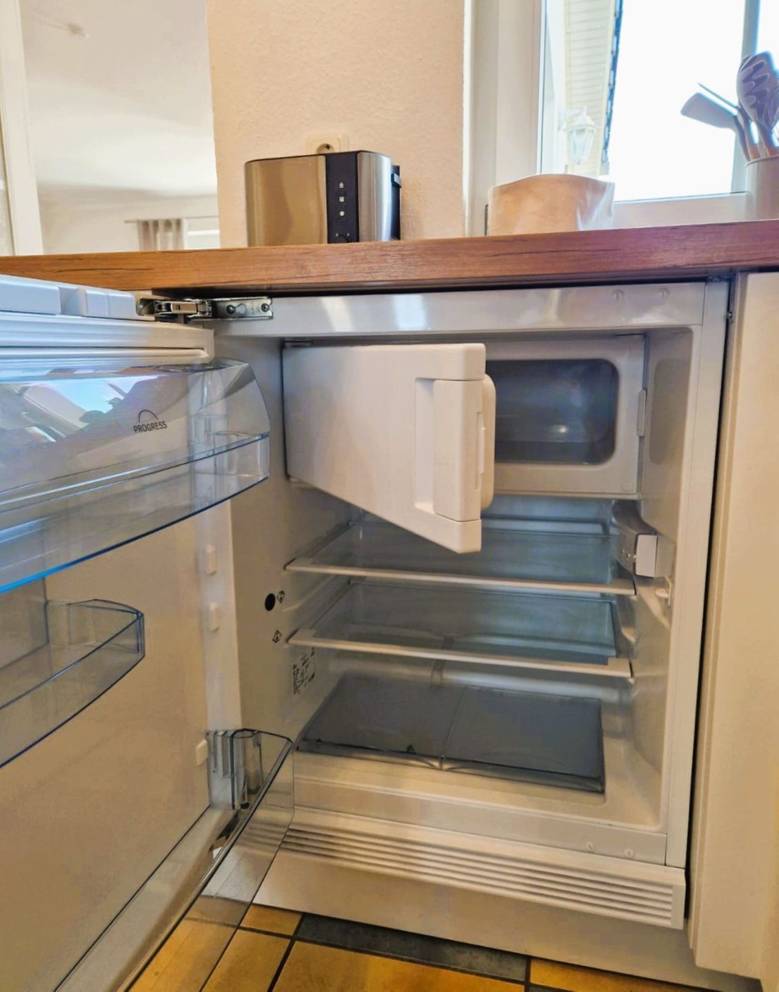 Une cuisine équipée d’un réfrigérateur encastré, d’un four à micro-ondes et d’un grille-pain.