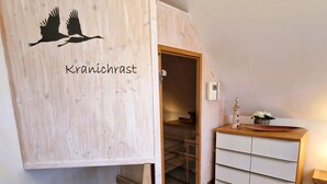 Un escalier en bois mène à une chambre située en mezzanine, sous un plafond en pente.
