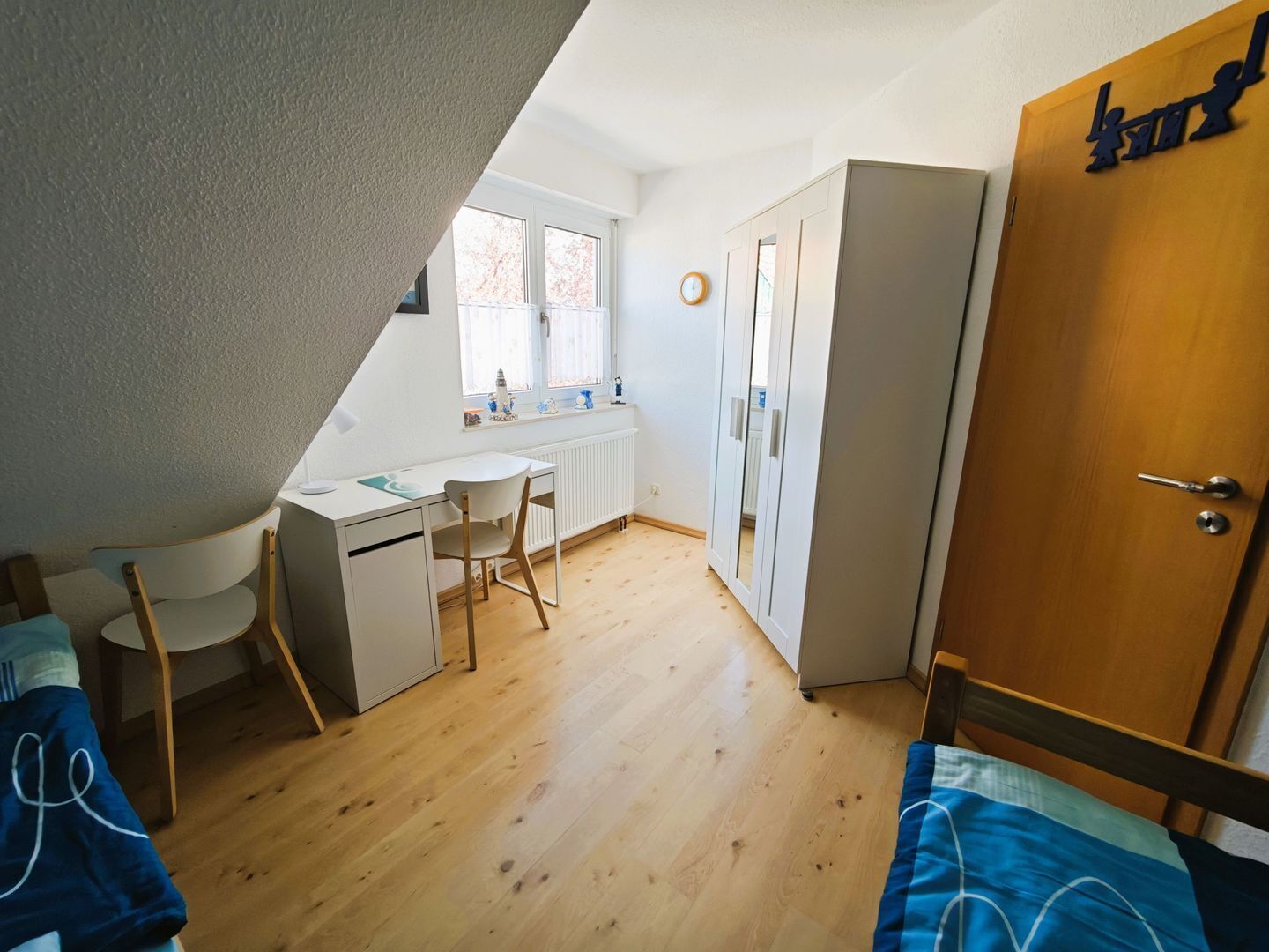 Une petite pièce bien éclairée, avec un bureau, une chaise et une armoire.