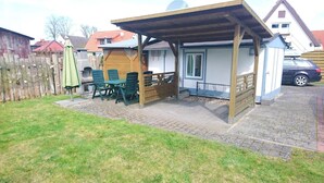 A covered patio area with outdoor seating and a small building structure. - Schulstrasse 10a (App) - cozy 1-room apartment (Zingst)
