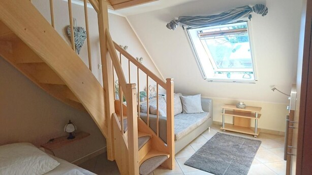 A room with a wooden staircase, a sofa, a small table, a window with a view, and a rug. - Schulstrasse 10a (App) - cozy 1-room apartment (Zingst)