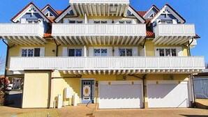 A multi-story building with a yellow facade, multiple balconies, and a garage entrance. - Fritz-Reuter-Str. 2 Whg. 7 "Sonnenuhr" - A lovingly furnished apartment (Zingst)