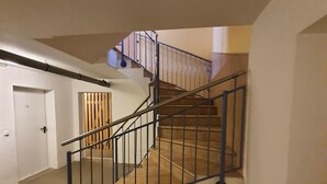 A staircase with a metal railing, carpeted floor, and a door in the background. - Fritz-Reuter-Str. 2 Whg. 7 "Sonnenuhr" - A lovingly furnished apartment (Zingst)