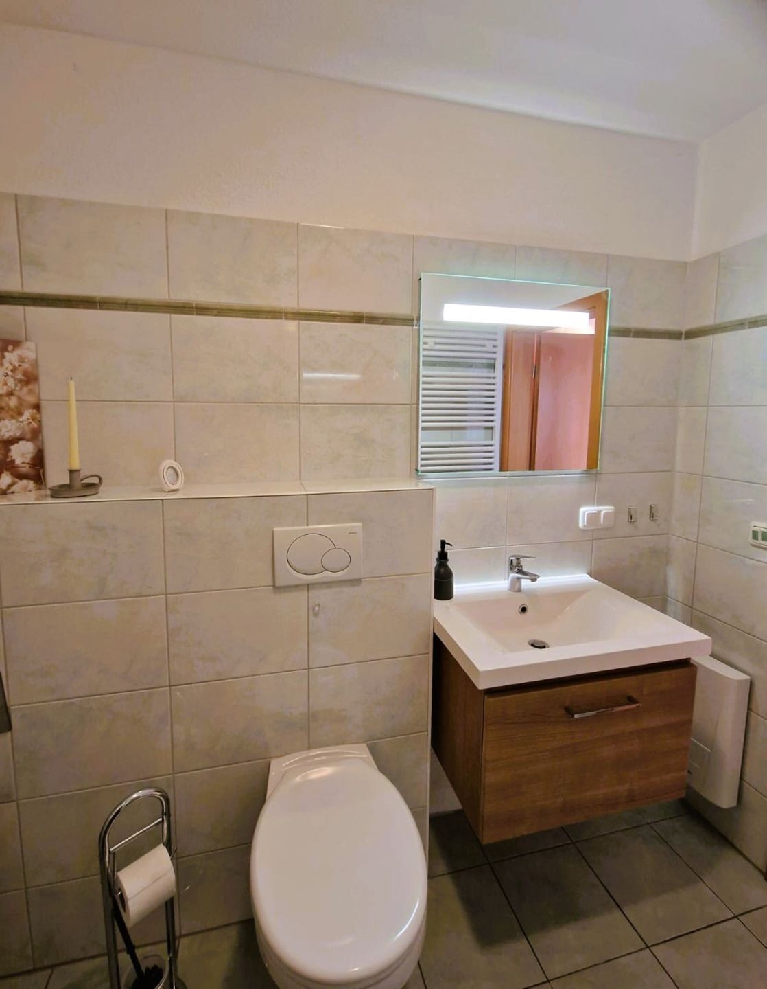 Een badkamer met toilet, wastafel en spiegel.