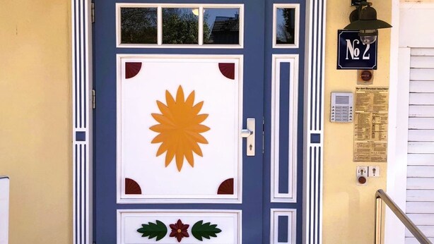 A blue door with a sun design, labeled "SONNENUHR," and a small sign with the number "2" on the right. - Fritz-Reuter-Str. 2 Whg. 7 "Sonnenuhr" - A lovingly furnished apartment (Zingst)