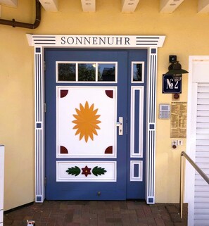 A blue door with a sun design, labeled "SONNENUHR," and a small sign with the number "2" on the right.