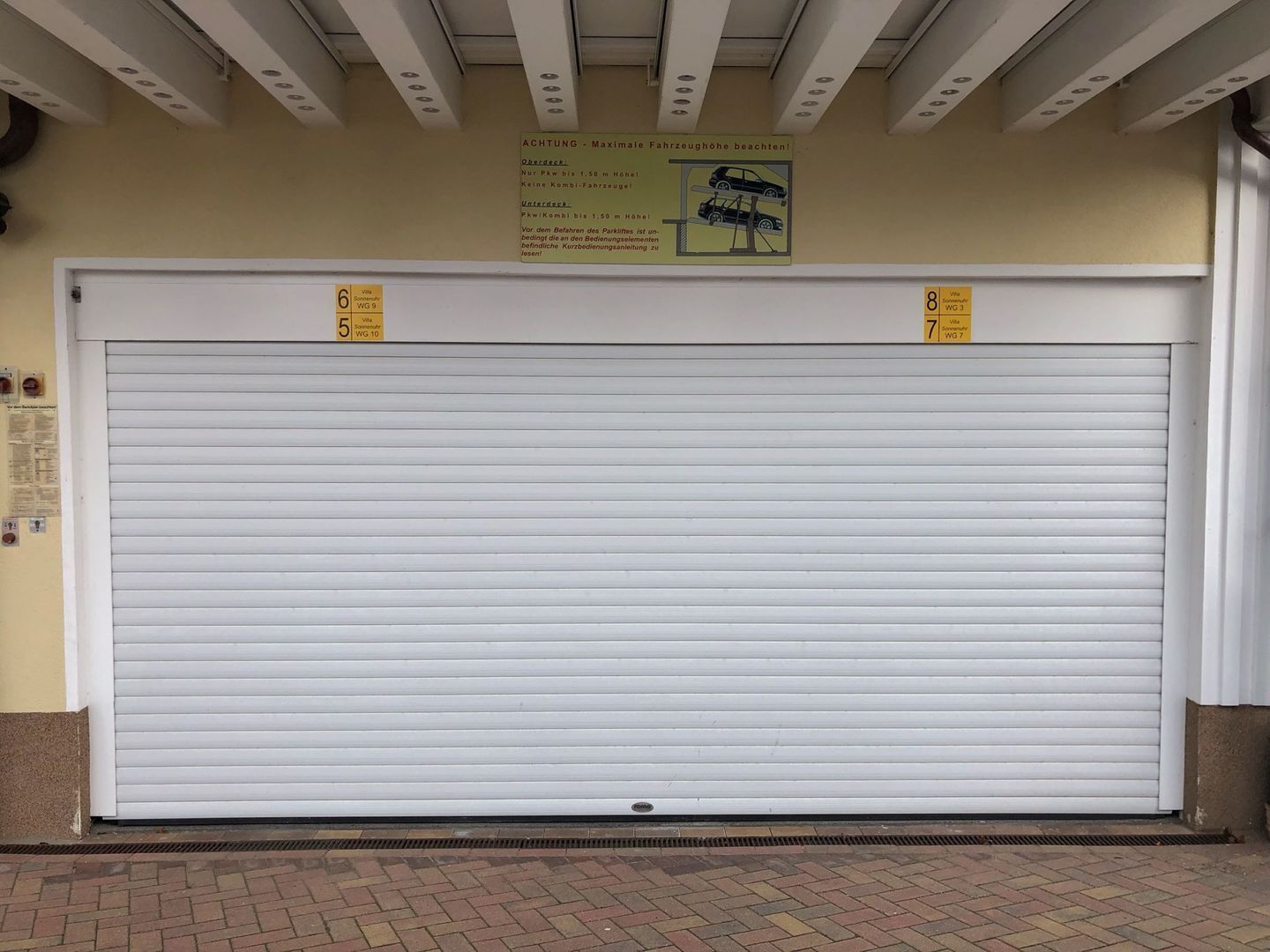 Une porte de garage fermée, avec un panneau au-dessus indiquant la hauteur maximale autorisée pour les véhicules.