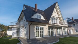 A two-story house with a large balcony, a garage, and a well-maintained lawn. - Haus Kranichsruh Whg.2.3 "strandgut" (Zingst)