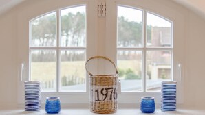 A room with a large arched window, a wicker basket with the number 197, and stacks of blue and white patterned containers. - Haus Kranichsruh Whg.2.3 "strandgut" (Zingst)