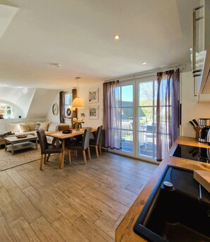 Eine moderne Küche mit Holzarbeitsplatte und integriertem Spülbecken, ein Essbereich mit Holztisch und Stühlen sowie eine große Schiebeglasdoor, die auf eine Außenpatio führt.