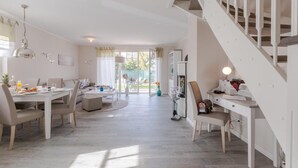 A spacious living area with a dining table, sofa, and a staircase. - Birkmaase 1a "Abendklang" - comfortable semi-detached house "Abendklang" is quiet (Zingst)