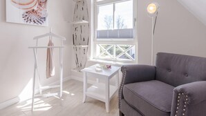 A modern, well-lit room with a grey sofa, a white table, and a window with a view. - Birkmaase 1a "Abendklang" - comfortable semi-detached house "Abendklang" is quiet (Zingst)