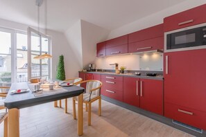 Une cuisine moderne avec des meubles rouges, un plan de travail noir et un four à micro-ondes en acier inoxydable.