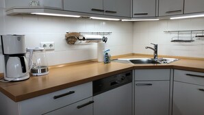 A modern kitchen with white cabinets, a stainless steel sink, a coffee maker, and a dish drying rack. - Martha-Müller-Grählert-Weg 8 Whg. 7 - Spacious, modernly furnished (Zingst)
