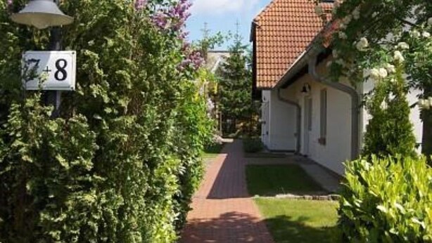 A residential street with a house number sign, a paved path, and lush greenery. - Martha-Müller-Grählert-Weg 8 Whg. 7 - Spacious, modernly furnished (Zingst)