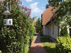 A residential street with a house number sign, a paved path, and lush greenery. - Martha-Müller-Grählert-Weg 8 Whg. 7 - Spacious, modernly furnished (Zingst)