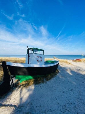 Una pequeña embarcación con toldo verde sobre una playa arenosa.