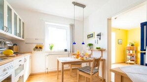 Une cuisine lumineuse avec des meubles de rangement en bois, une table à manger et une fenêtre.