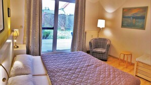 Une chambre à coucher avec un lit, une chaise, une petite table et un tableau accroché au mur.