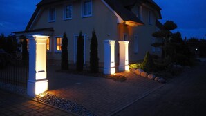 Ein zweistöckiges Haus mit gut beleuchtetem Eingangsbereich und einer Auffahrt zur Haustür.